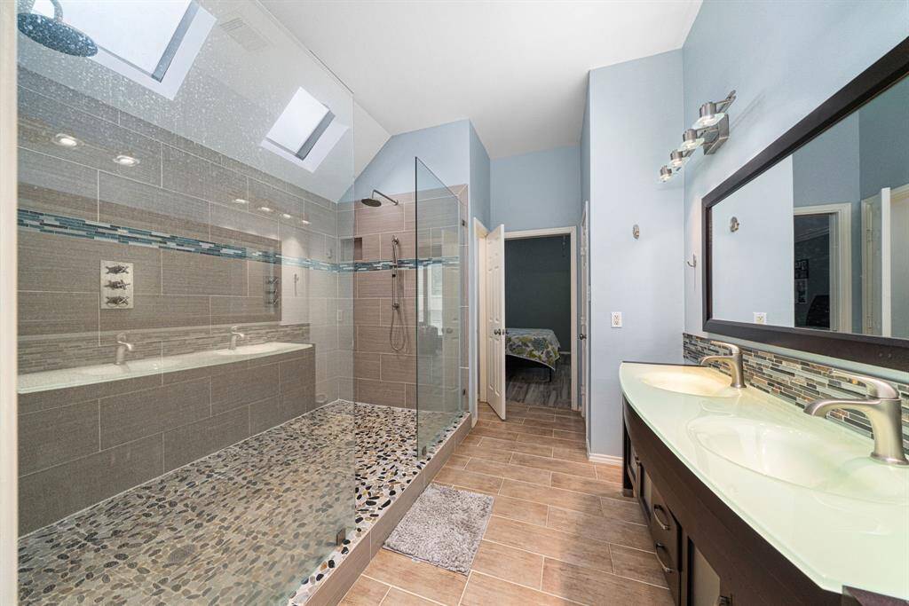 Indulge in this expansive ensuite bathroom, designed like a high-end spa retreat. The oversized walk-in shower features dual showerheads for a lavish experience, while two custom skylights bathe the space in warm, natural light.