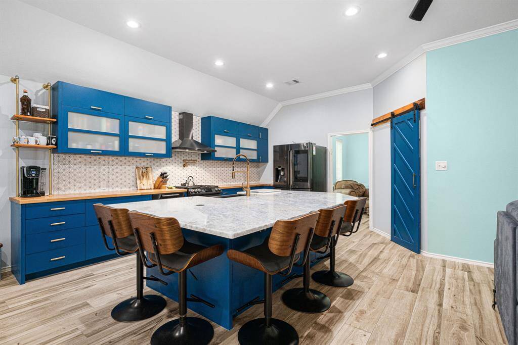 Step into this stunning, fully remodeled high-end kitchen, where sleek design meets unparalleled functionality. Elegant backsplash perfectly complements the custom modern cabinets, packed with premium upgrades like lazy Susans, pull-out shelves, and soft-close drawers/doors for effortless organization. The massive center island is a showstopper, featuring a gorgeous single-slab stone countertop and a pull-up bar-perfect seating for casual dining and entertaining. Barn door opens into a large walk-in pantry