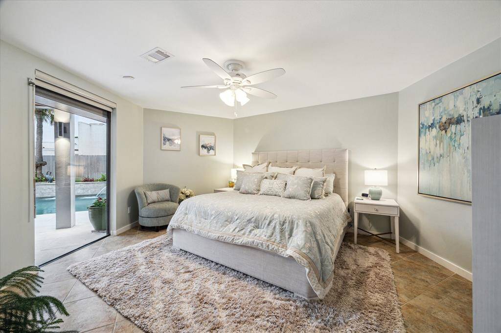 The second bedroom is large and has natural light pouring in through a sliding glass door that opens to a poolside patio, offering a serene view.