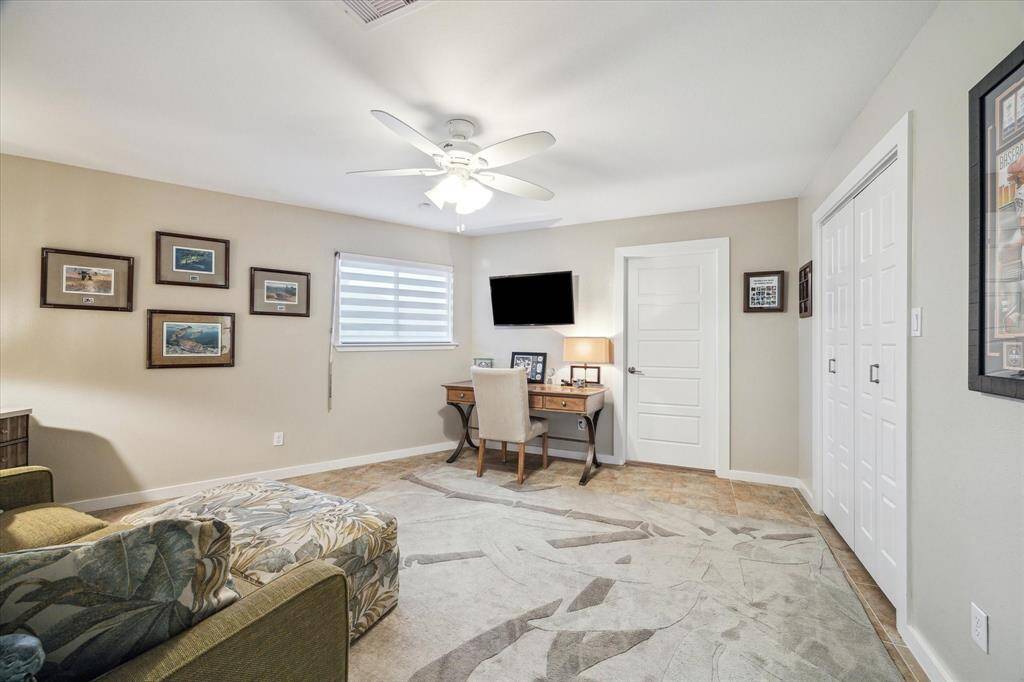 This fourth bedroom/office is bright and features neutral walls, a ceiling fan, seating area ideal for a home office or guest room.