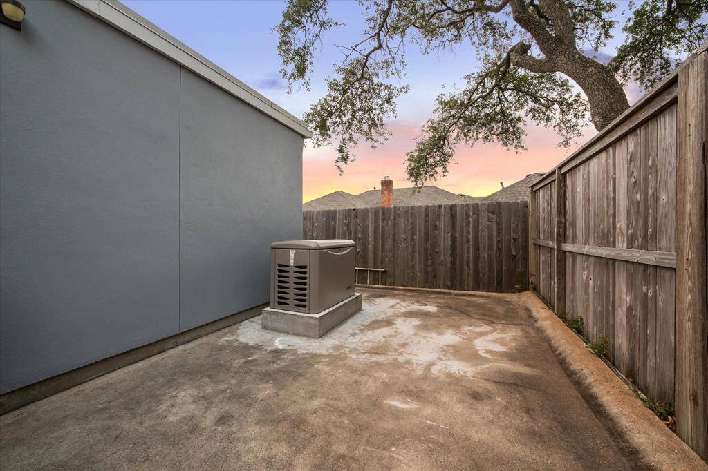 This photo shows a small, enclosed outdoor area with a concrete surface with a large whole house generator.