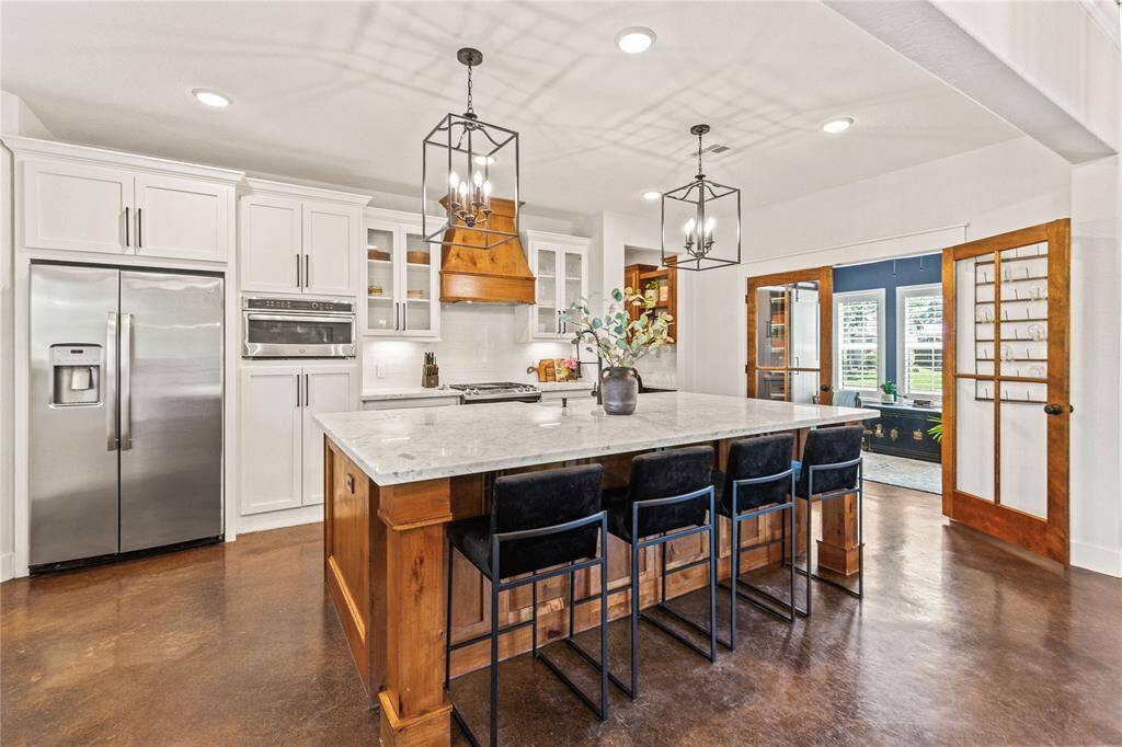 Spacious kitchen with large island, stainless appliances, gas stove, custom vent hood, and large walk-in pantry.