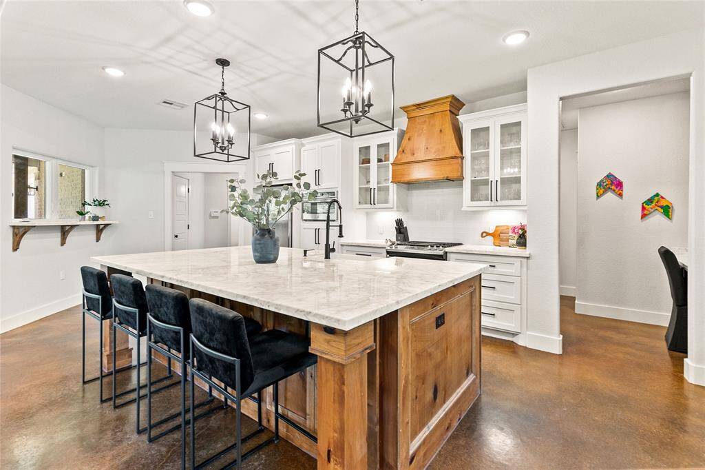 Spacious kitchen with large island, stainless appliances, gas stove, custom vent hood, and large walk-in pantry.
