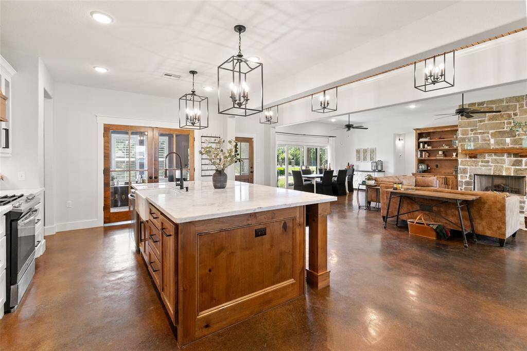 Spacious kitchen with large island, stainless appliances, gas stove, custom vent hood, and large walk-in pantry.