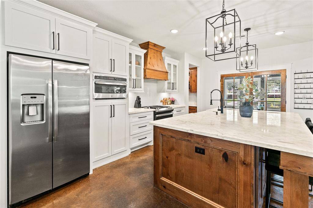 Spacious kitchen with large island, stainless appliances, gas stove, custom vent hood, and large walk-in pantry.