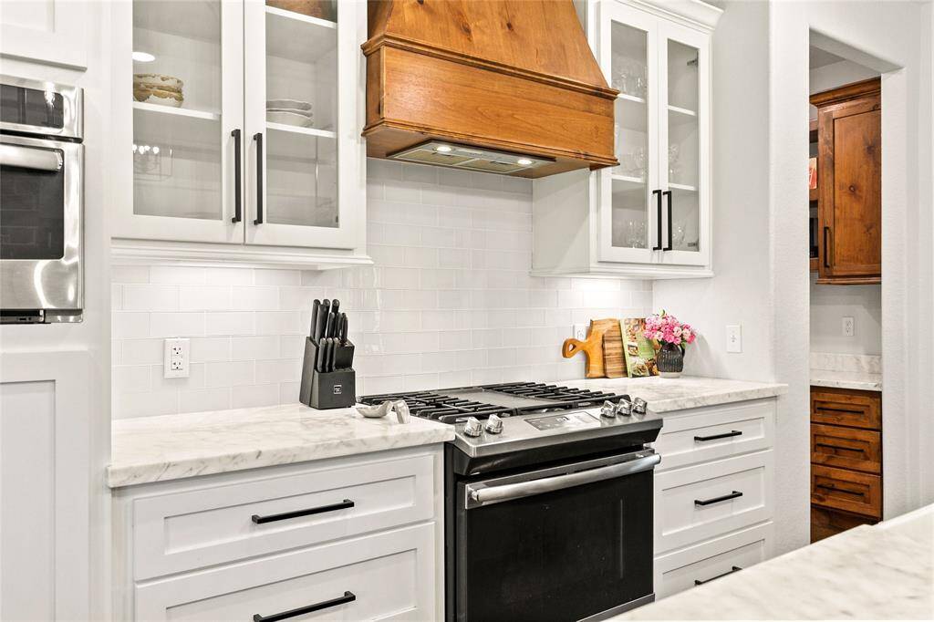 Spacious kitchen with large island, stainless appliances, gas stove, custom vent hood, and large walk-in pantry.
