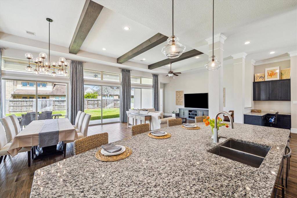 The oversized granite island, with chic overhead lighting, offers plenty of workspace for meal prep and cleanup, while convenient bar seating on the opposite side provides the perfect spot for casual dining or morning coffee.