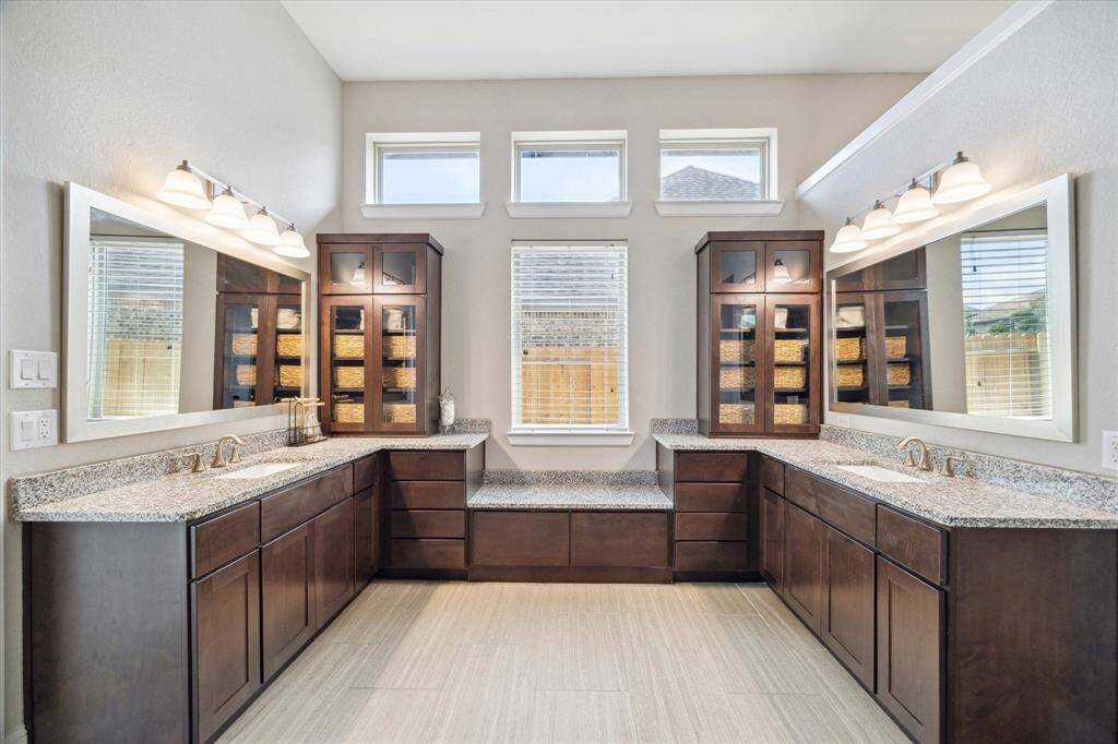 Two separate vanities, along with thoughtfully designed storage solutions, ensure plenty of space for all your essentials. Highlights include oversized drawers, a convenient built-in bench, elegant glass-front cabinets, and expansive storage in each vanity, combining both function and style in this luxurious retreat.