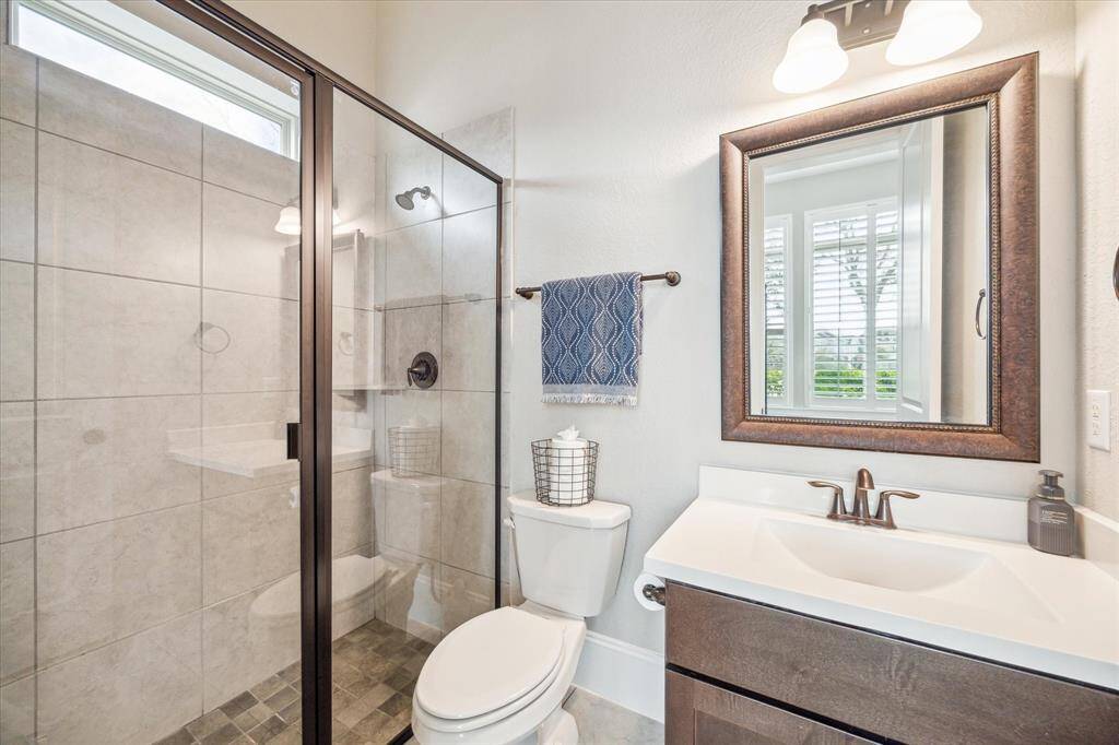 The first floor guest ensuite features a single sink vanity with a framed mirror and vanity lights above and a convenient walk-in shower.