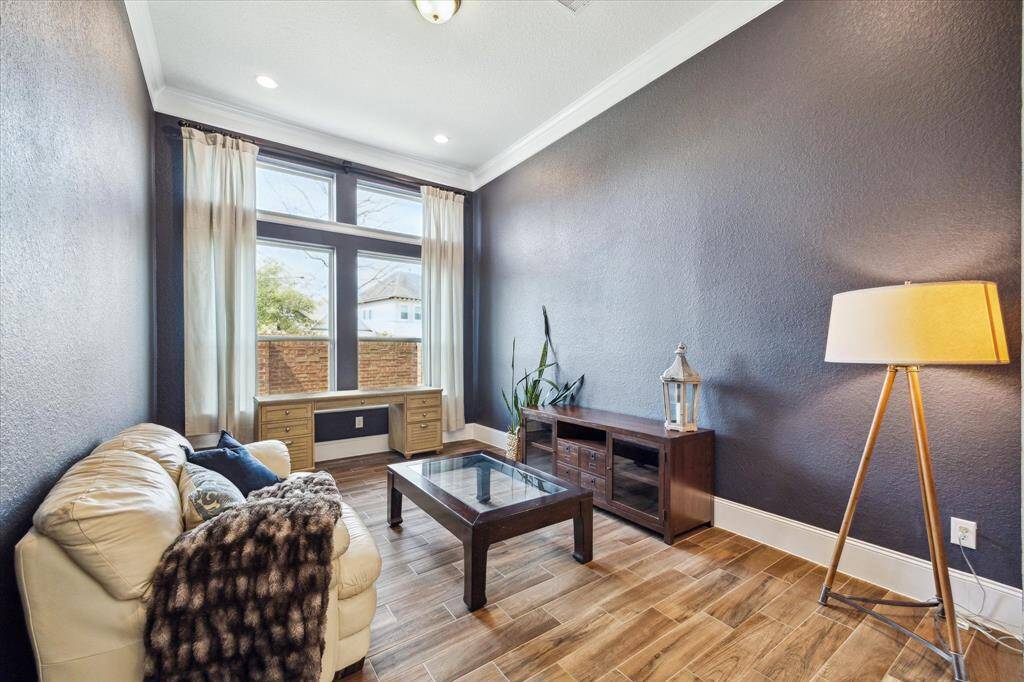 The first-floor flex room features designer paint, stacked windows, thick crown molding and recessed light with ample space for lounging