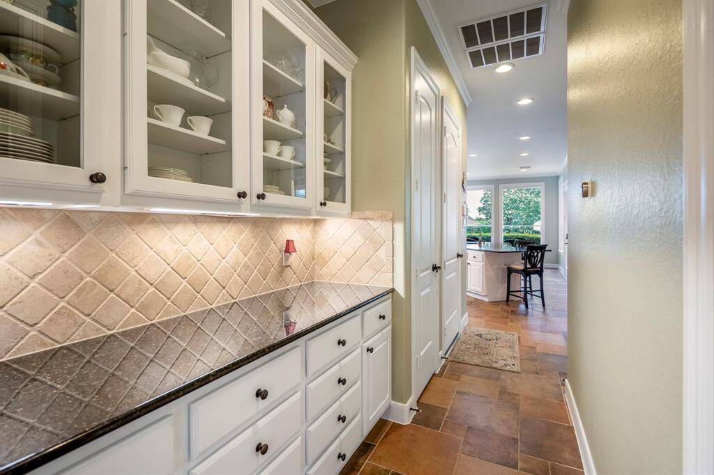 A highly requested Butler's Pantry offers lots of upper and lower cabinetry (with drawers), a tiled diagonal backsplash, under counter lighting and glass fronted upper cabinets.