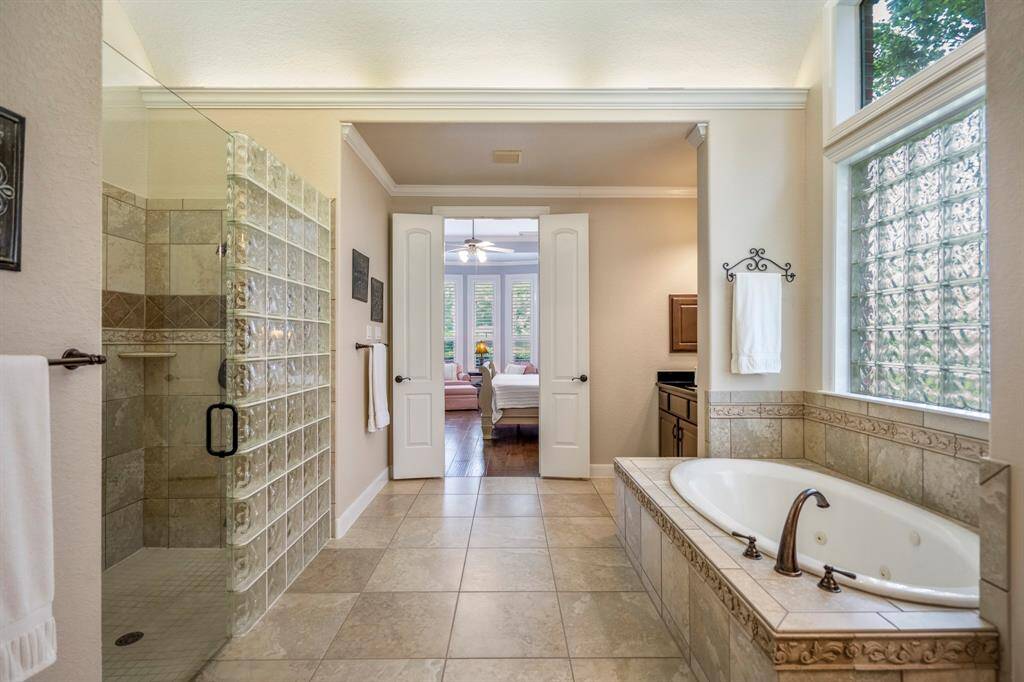 Keeping a cohesive look, you will find the walk-in shower opposite the tub, surrounded by a glass block wall.