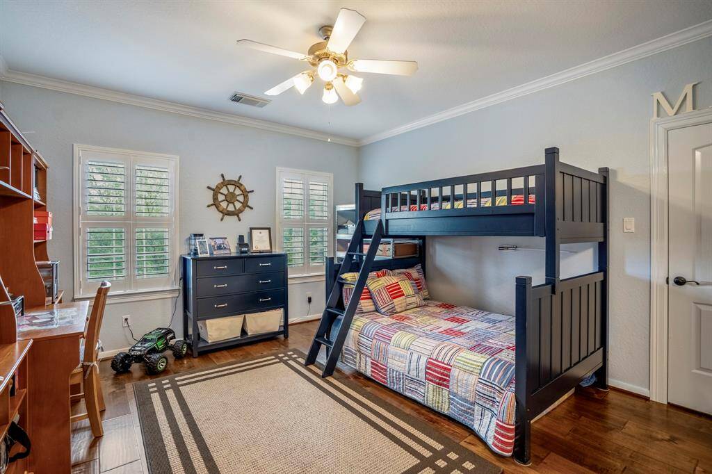 Upstairs secondary bedroom features the same gorgeous wood floors, powder blue walls, and large windows with plantation shutters to diffuse light.