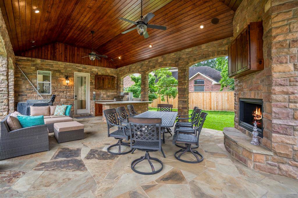 Exterior lighting in the wood beaded ceiling provides visibility and adds mood to an outdoor space. Enjoy the ambiance of the custom built stacked stone fireplace as well as the kitchen grill, and breakfast bar.