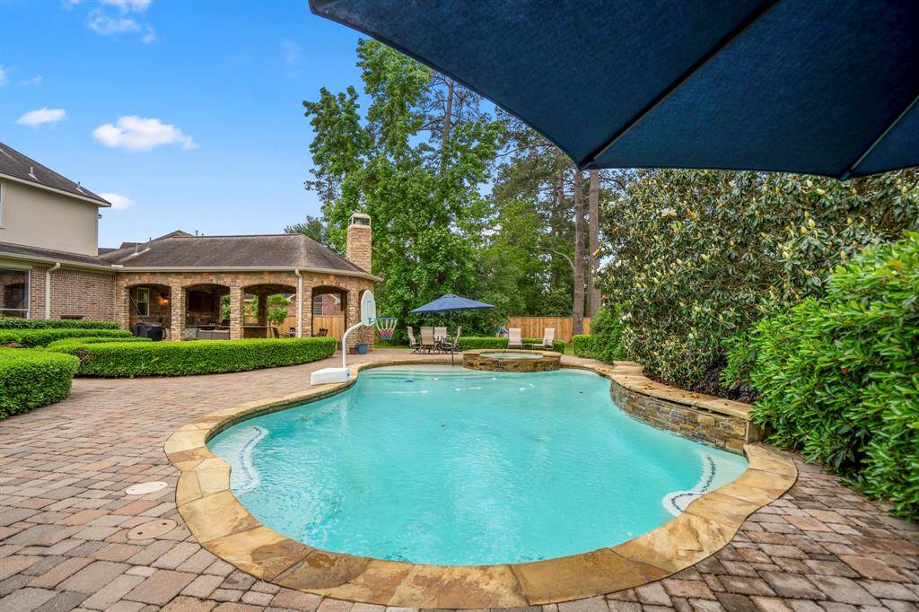 Neutral-toned stone pavers lend a harmonious feel to the outdoor area as it continues out to the sparkling pool and raised spa surrounded by the lushly landscaped backdrop.