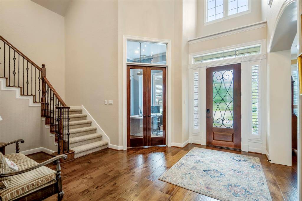 Two-story foyer has stunning gleaming hardwoods throughout & wrought iron staircase with natural light streaming into the space.
