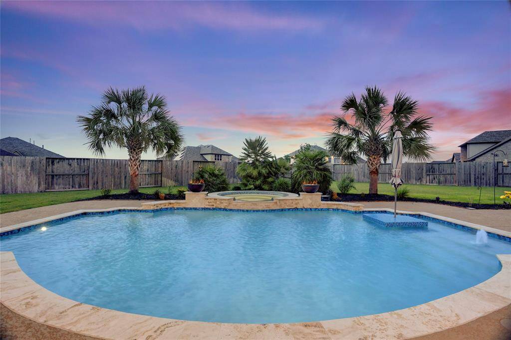 This breathtaking backyard retreat features a sparkling resort-style pool with a built-in spa, framed by tropical palm trees and lush landscaping. Whether you’re unwinding in the hot tub or hosting poolside gatherings, this private oasis is designed for luxury and comfort.