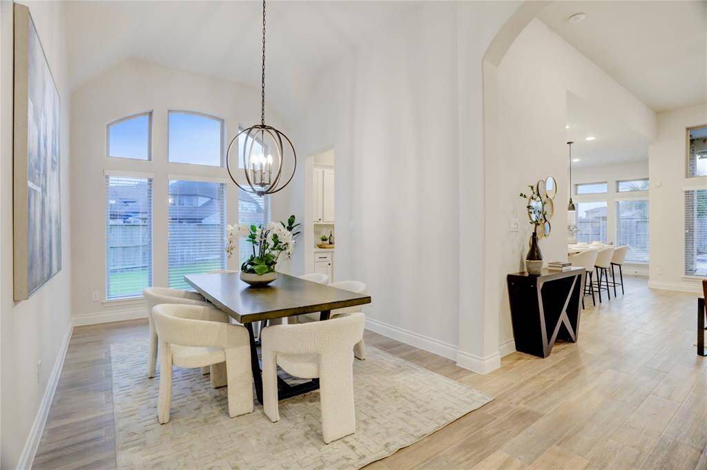 A seamless transition from the dining room to the kitchen showcases open-concept living, perfect for entertaining. Natural light fills the space from large windows overlooking the backyard.