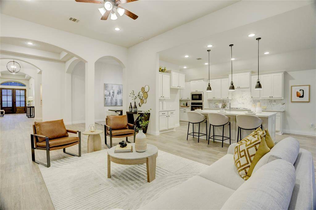 View of the open floor plan from living to kitchen, showcasing continuous natural light, pendant lighting, and generous seating areas for casual dining and entertaining.