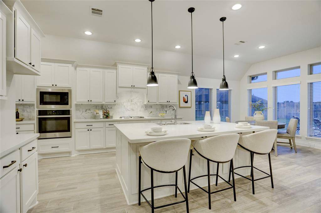 This bright and spacious kitchen is designed for both everyday living and effortless entertaining. Featuring a generous island with bar seating for four, sleek pendant lighting, and abundant cabinetry for all your storage needs. The layout offers a perfect balance of functionality and style, with a cozy breakfast nook and expansive windows that flood the space with natural light.
