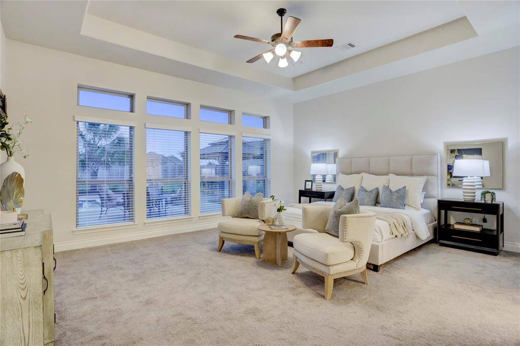 Step into this oversized primary suite bathed in natural light. From a full wall of windows overlooking the resort-style backyard, this room offers space to breathe, unwind, and truly live. The tray ceiling adds a touch of architectural elegance, while the generous layout easily accommodates a king bed, sitting area, and more. Whether you're enjoying a slow morning with coffee in hand or winding down after a long day, this luxurious retreat is your personal sanctuary.