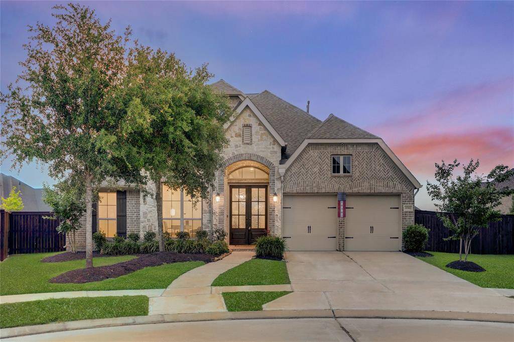 A stunning Perry Homes elevation featuring a mix of stone and brick with arched double-door entry, manicured landscaping, and a 3-car tandem garage.