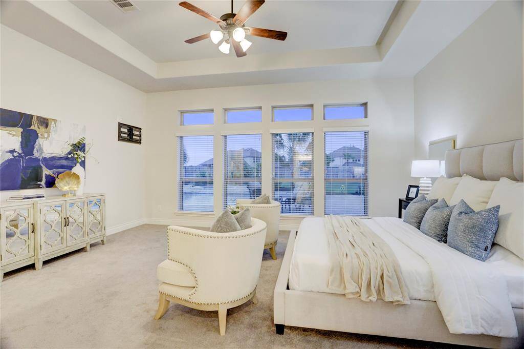 Wake up to peaceful poolside views in this light-filled primary suite. The tray ceiling adds architectural design, while plush carpet and neutral tones provide a calm, inviting atmosphere you’ll love coming home to.