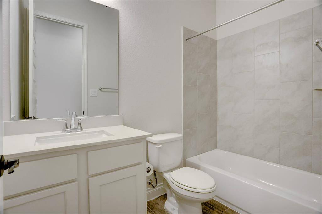This secondary bathroom blends function with fresh, modern style. Featuring sleek quartz countertops, cabinet storage, and a classic tub/shower combo wrapped in clean, neutral tile.