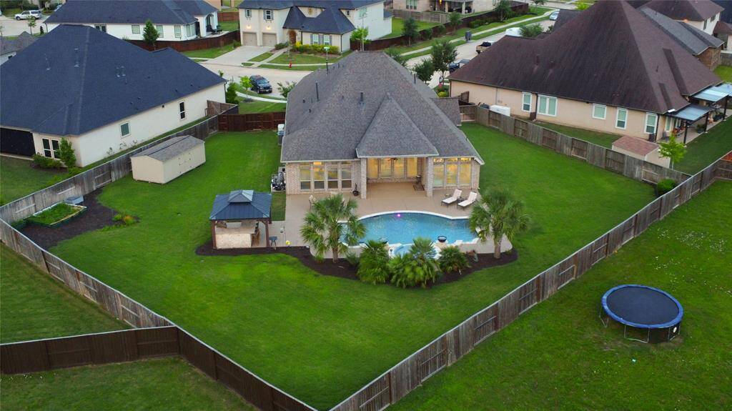From above, the scale of the backyard comes to life—showcasing the well-designed layout with pool, gazebo, and multiple entertaining zones. The lot is fully fenced for privacy and includes a shed for extra storage and a Generac generator for peace of mind.