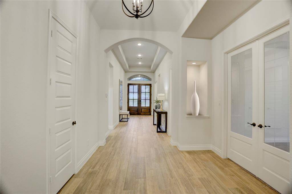 Step into a soaring foyer with tray ceilings, stylish niches, and elegant lighting. The wide hallway flows seamlessly into the heart of the home, creating an open atmosphere.