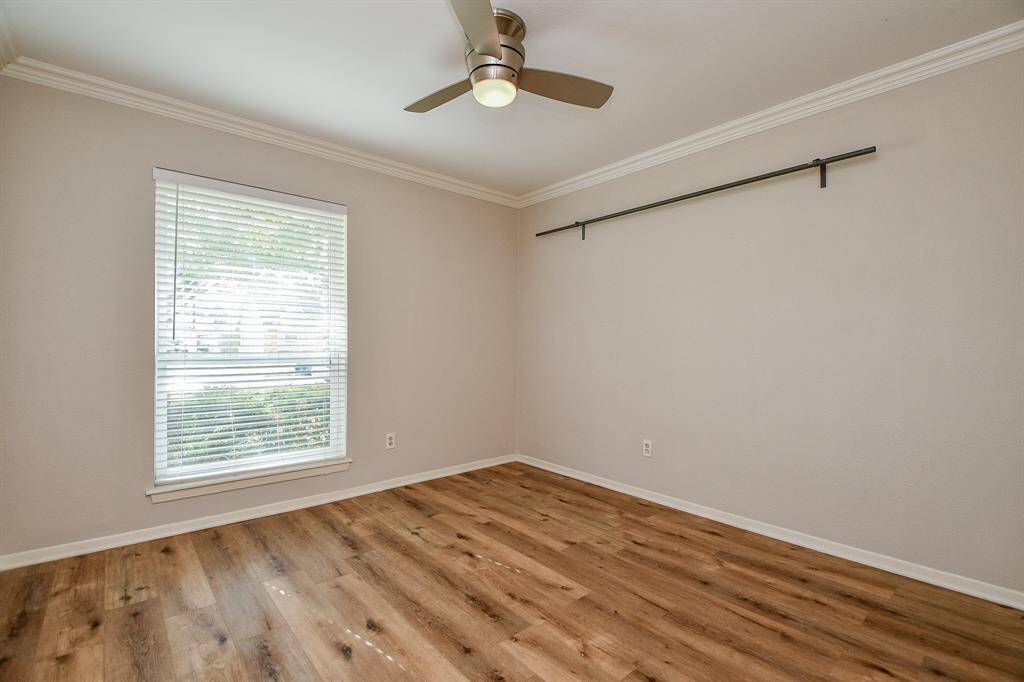 A spacious secondary bedroom is graced with wood flooring and soothing colored walls. The great big window brings tons of natural light.