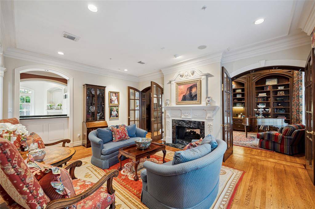 The formal living room features a custom-built, double-sided gas log fireplace. The mantel is adorned with antique reclaimed wood arches from New Orleans, adding a touch of historic charm. The room is wired for sound and opens seamlessly to the bar, creating an inviting space for entertainment.