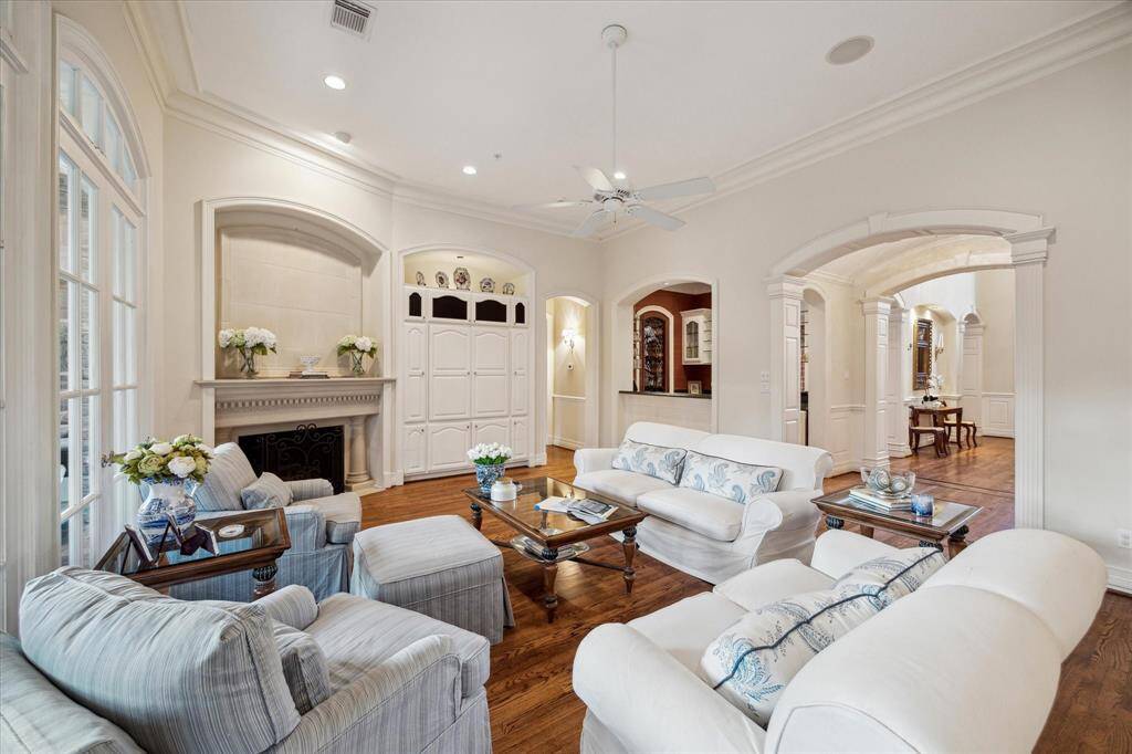 The family room exudes warmth and connectivity, seamlessly linking to the kitchen and other key areas of the home. A cast stone gas log fireplace serves as a striking focal point, radiating cozy charm, while a built-in media cabinet adds both functionality and style. The rich hardwood floors ensure seamless transitions, further elevating the room's elegant and welcoming ambiance.