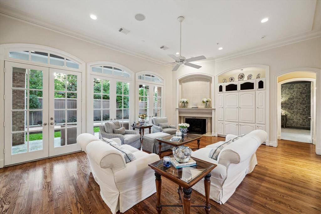 French door windows frame picturesque views of the back patio, inviting natural light to enhance the room's welcoming atmosphere. The room offers easy access to the primary suite and bar, ensuring convenience and connectivity.