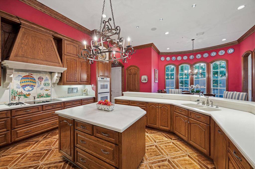 The kitchen serves as the heart of the home, featuring a custom hand-painted tile backsplash with intricate cast stone vent hood details and a French-style wrought iron pot rack. There is an exceptional abundance of counter space and cabinetry, catering to the discerning chef. Under-counter lighting and two custom-built holders for paper towels or foil showcase the meticulous attention to detail.