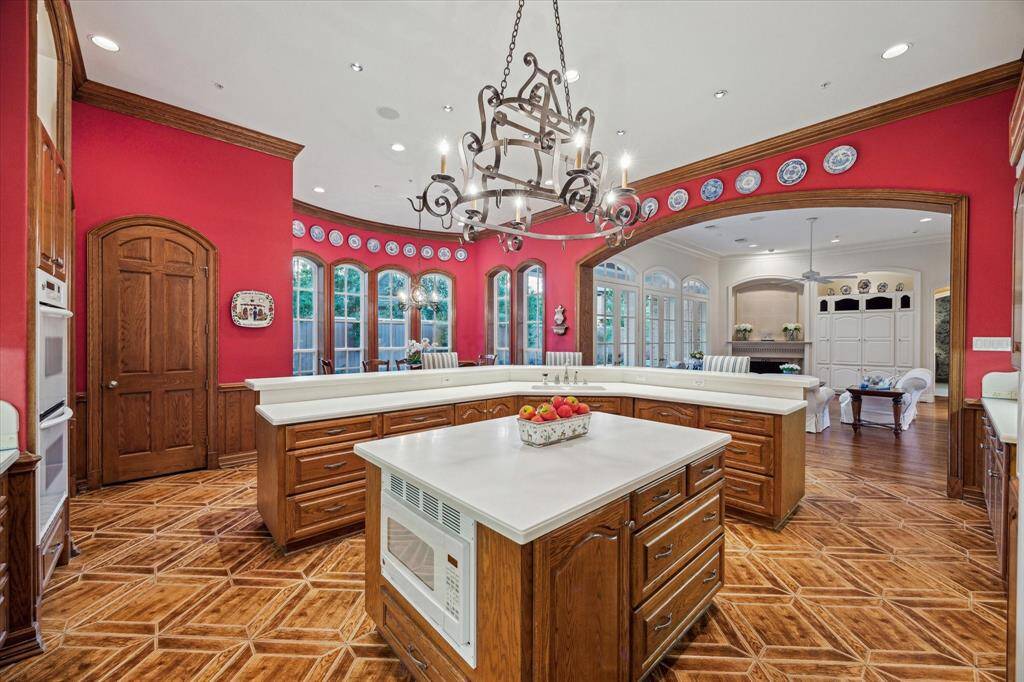 Wood tile flooring creates a seamless transition from the family room, while Corian countertops showcase clean lines. The cabinetry includes a heavy-duty mixer lift, adding to the kitchen's functionality. Double ovens and a built-in microwave make cooking effortless.