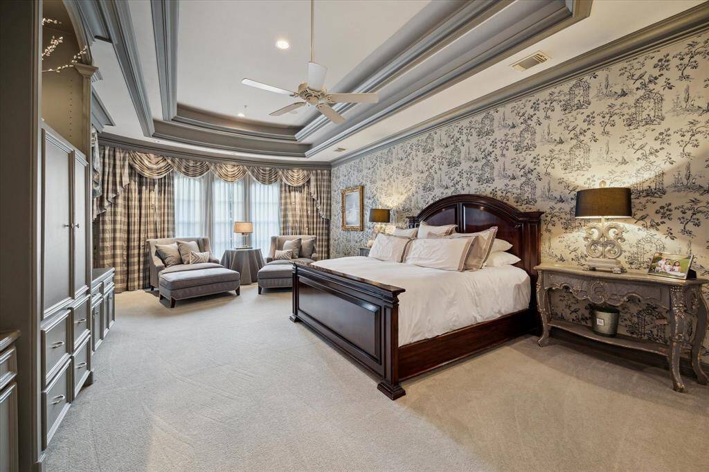Conveniently located on the first floor, the primary suite welcomes you with custom-created toile wallpaper, a tiered ceiling with warm uplighting, and a wall of built-ins. The private door to the exterior patio offers a serene retreat.