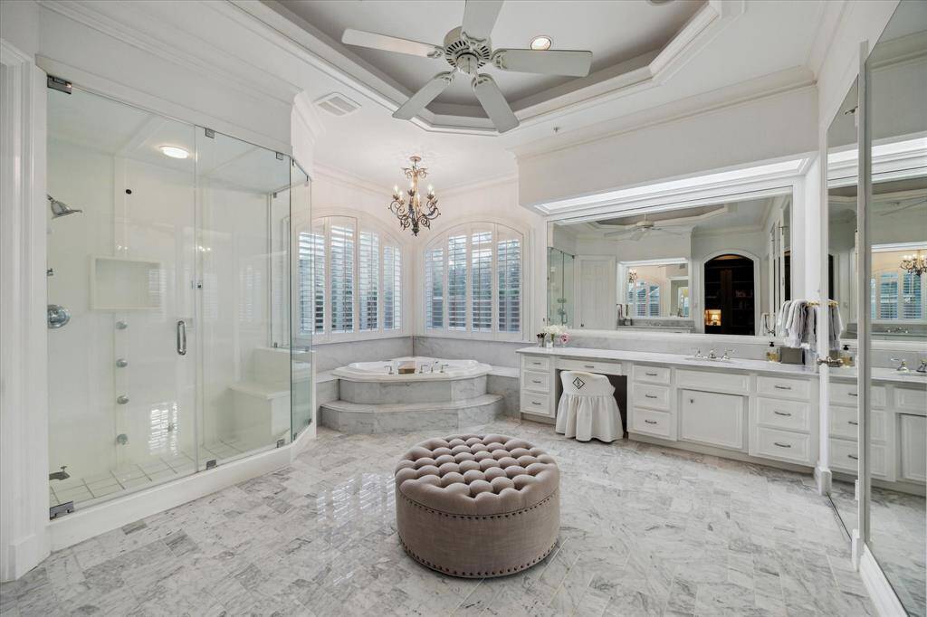 Stepping into the primary bathroom, you are welcomed by Carrera marble flooring laid in a charming herringbone pattern. The serene space includes double sinks, a jetted tub, a standalone shower, and a private water closet. Behind the wall of mirrors, you'll find an expansive walk-in closet.