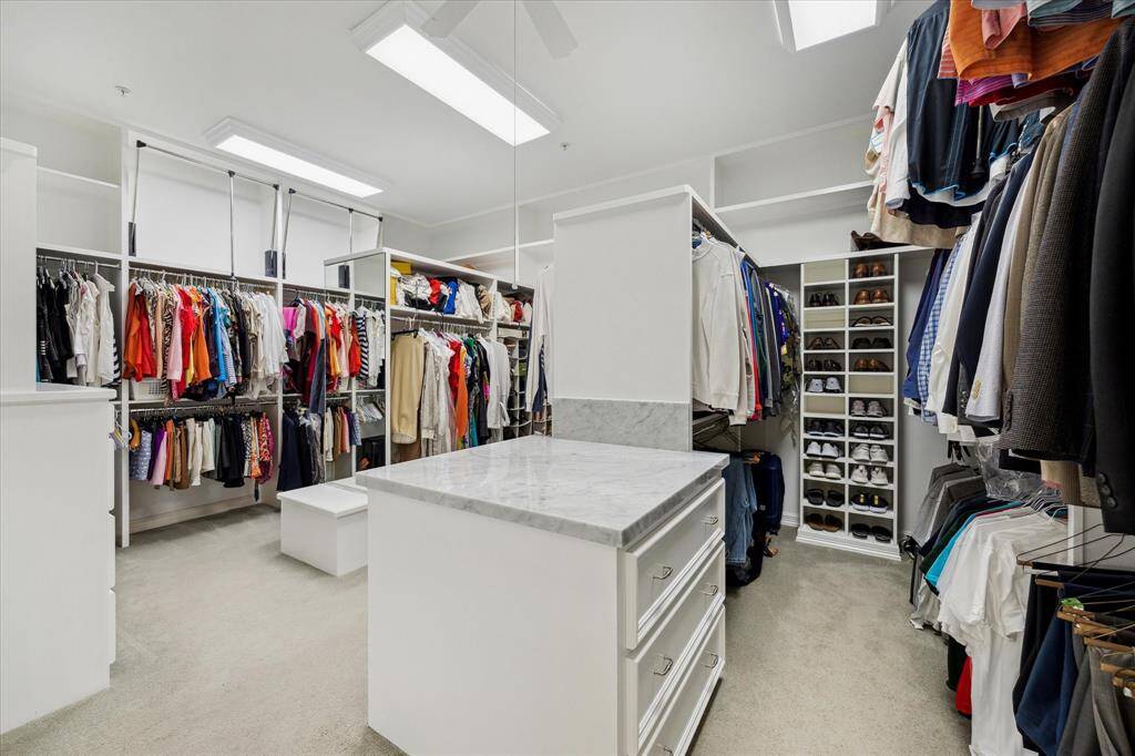 An exceptional, spacious walk-in closet features built-in drawers and storage, and is complemented by luxurious Carrera marble countertop.