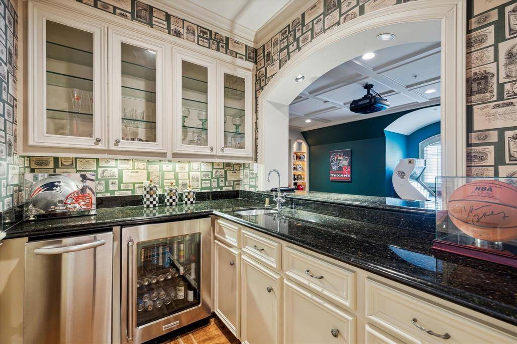 Conveniently located upstairs and open to the media room, the secondary bar is perfect for entertaining. It features an ice maker, beverage fridge, elegant glass shelving, and a sleek sink.