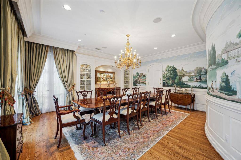 The dining room boasts exquisite hand-painted wallpaper by Gracie, French doors that open to an outdoor terrace, and built-in cabinets for china, adorned with rope lighting and a niche. Additionally, the room is wired for sound, enhancing the ambiance.