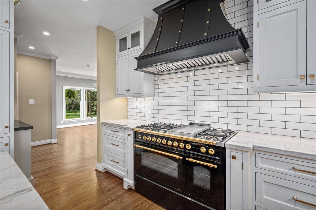 Featuring a stunning Hallman stove range from Italy, paired with a custom vent hood, this kitchen offers both style and functionality for the most discerning chef.