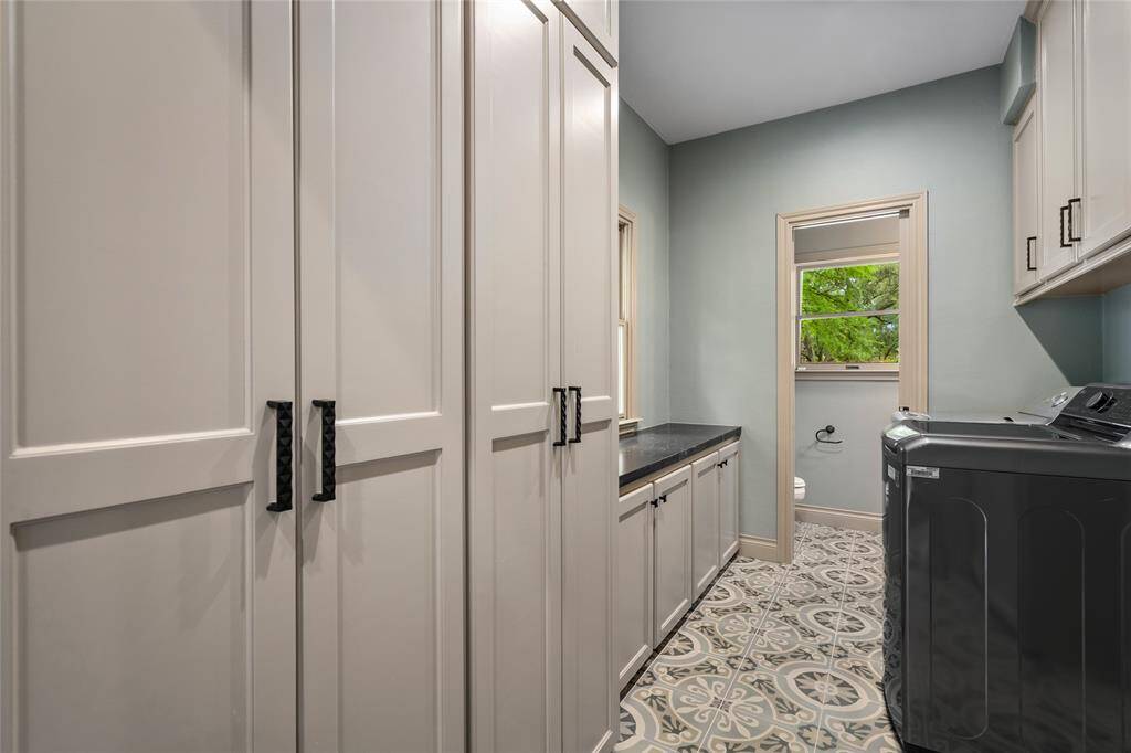 Spacious and functional laundry room with ample cabinetry and counter space for sorting and folding, flanked by half bathroom.