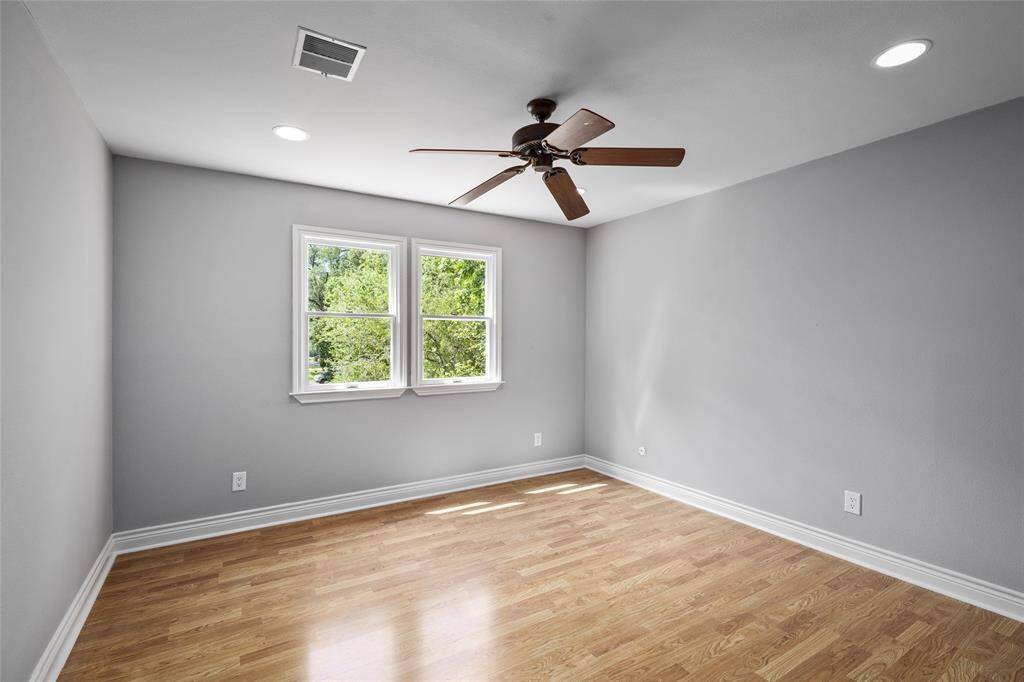 Bright and airy secondary bedroom featuring a generous walk-in closet and charming views of the front yard with mature trees and circle driveway.