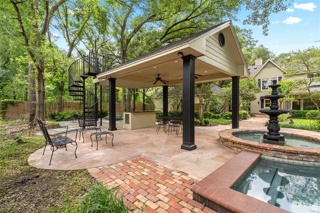 Spacious covered cabana featuring a spiral staircase leading to a second-level balcony with scenic views. Equipped with surround sound and kitchen, including a fridge and sink, this outdoor entertaining space is perfect for hosting gatherings or relaxing in style.