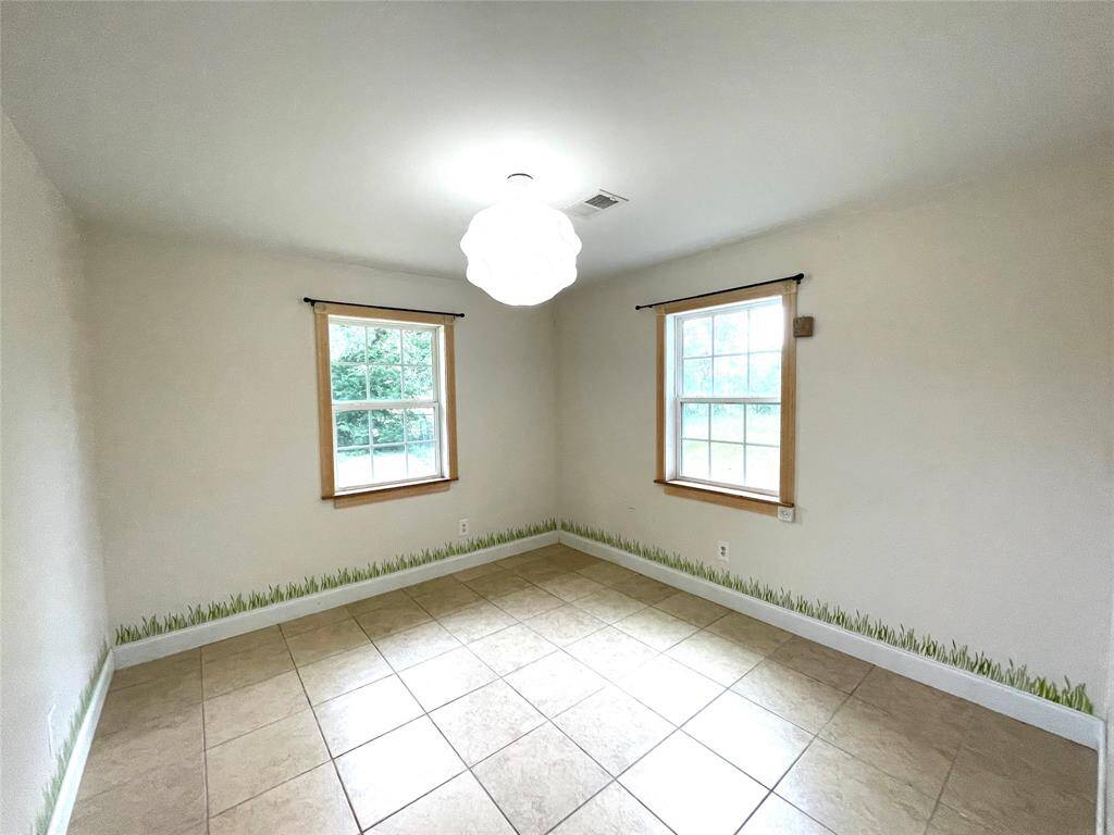 Secondary bedroom with corner windows and tile flooring.