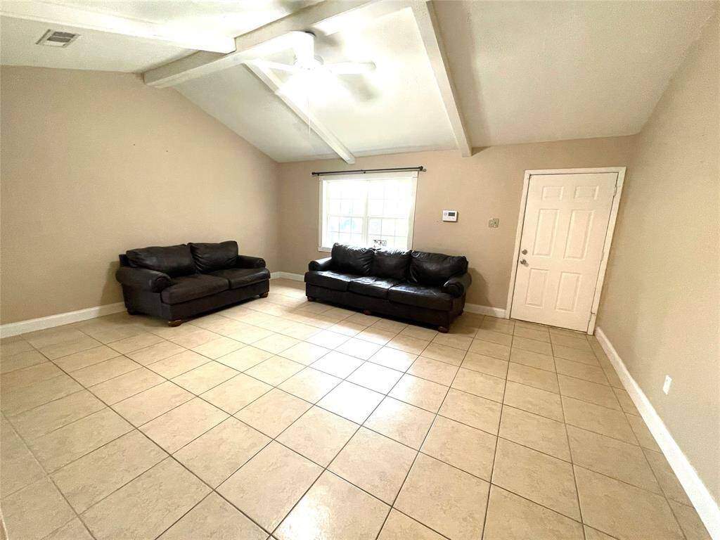 Living room with high ceilings, tile floors, and natural light.