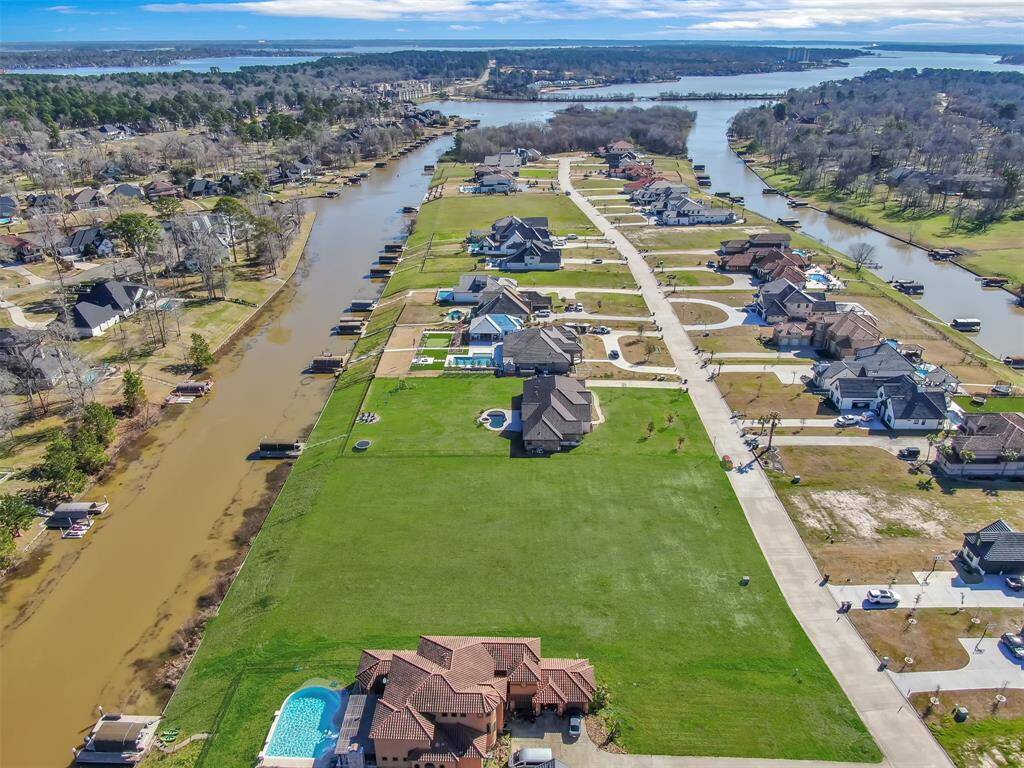 This aerial photo shows a residential waterfront community with canal access, featuring spacious homes with private docks, offering a blend of luxury and tranquility, with open green spaces and water views.