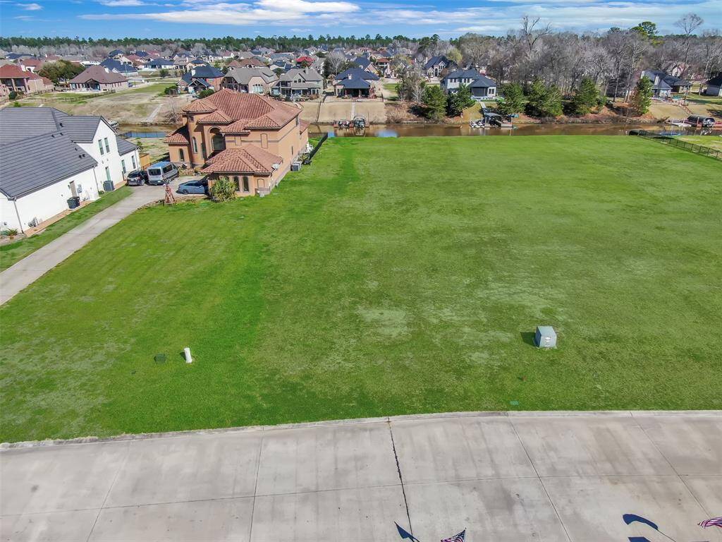 This is an aerial view of a spacious, undeveloped residential lot in a well-established neighborhood, surrounded by single-family homes, with potential for a custom build.