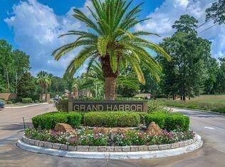 The photo shows the landscaped entrance to the Grand Harbor community, featuring a prominent palm tree and a sign with the community's name, a well-maintained and welcoming neighborhood.